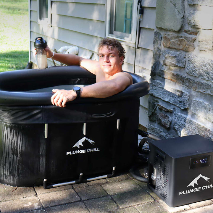 Young man in a portable PLUNGE CHILL tub on a patio, with chiller set to 43°F.