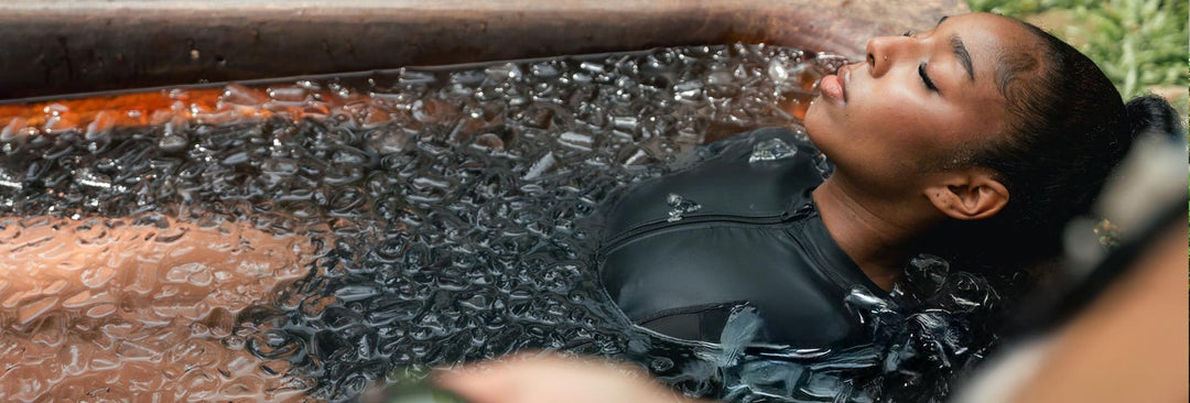 Woman fully submerged in ice bath with bubbles showing intense cold water immersion for athletic recovery and mental toughness.