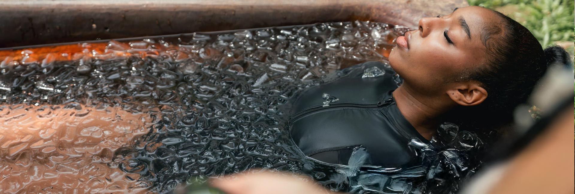 Woman fully submerged in ice bath with bubbles showing intense cold water immersion for athletic recovery and mental toughness.