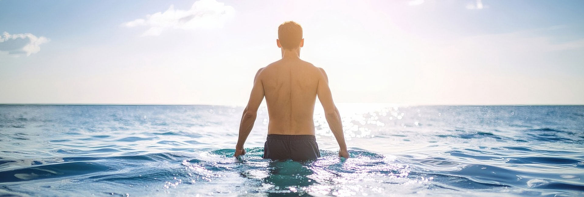 Man practicing cold water therapy in ocean for natural cold plunge benefits and muscle recovery.