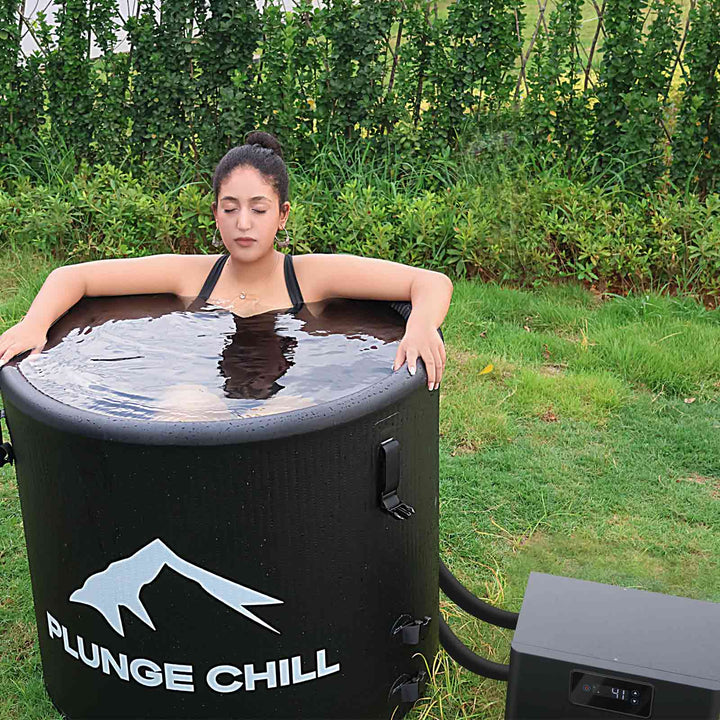 Fit woman using portable PVC cold plunge tub alone for daily wellness routine outside.