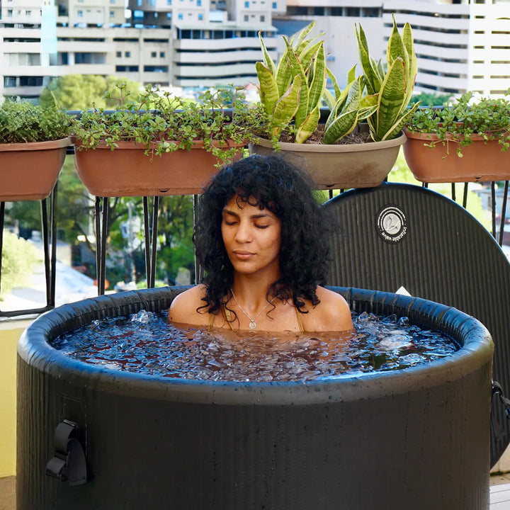 A woman is taking a ice bath on the balcony of her home.