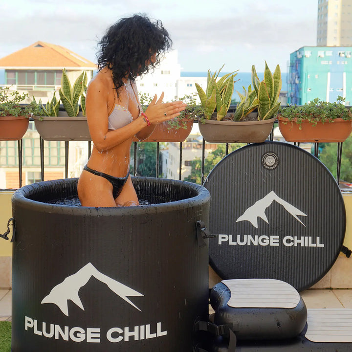A woman stands in a Plunge Chill ice bath for a cold plunge.