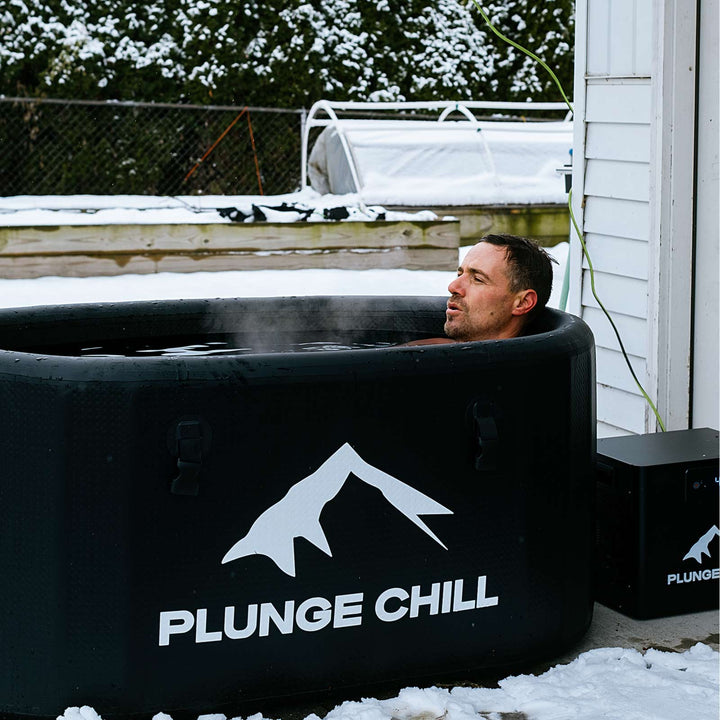 Man calmly enjoying a cold plunge in a Plunge Chill inflatable tub with chiller during an outdoor session