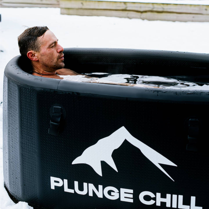 Man relaxing in a Plunge Chill inflatable cold plunge tub during an outdoor ice bath session