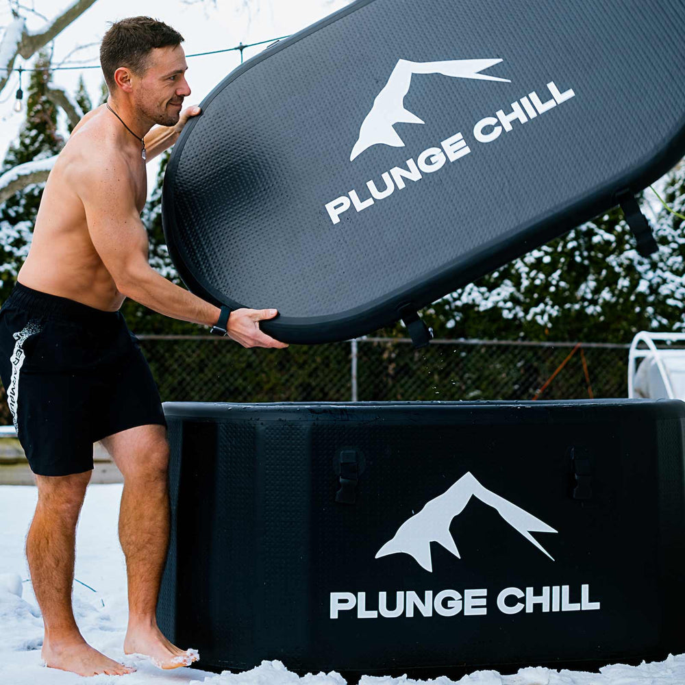 Athlete lifting the lid of a Plunge Chill inflatable cold plunge tub with chiller outdoors in winter conditions